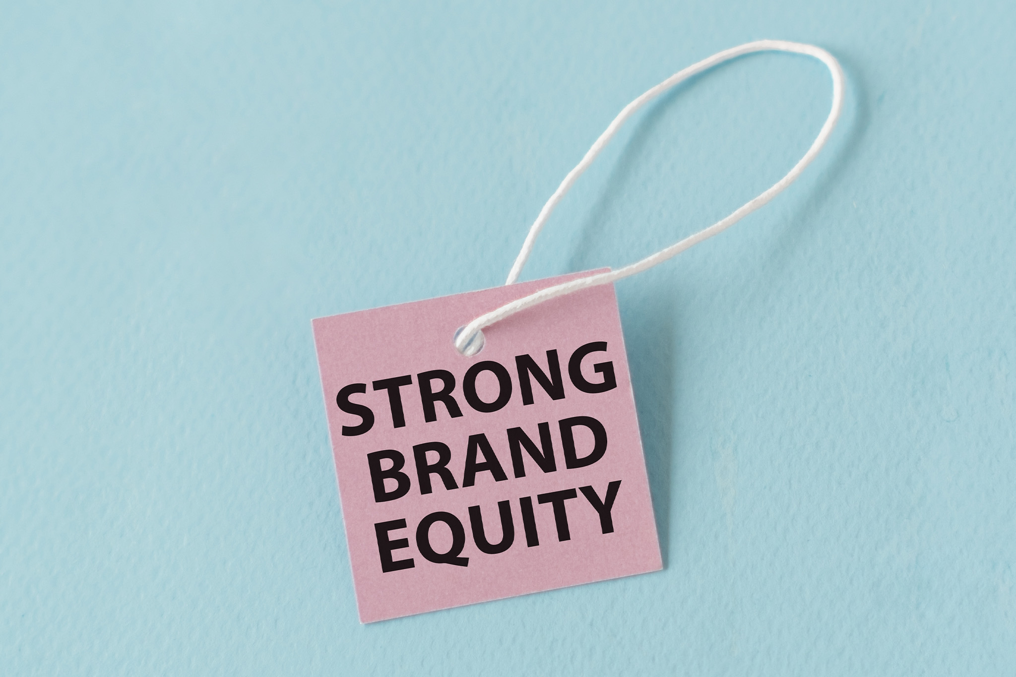 a square piece of paper on a string that says strong brand equity.