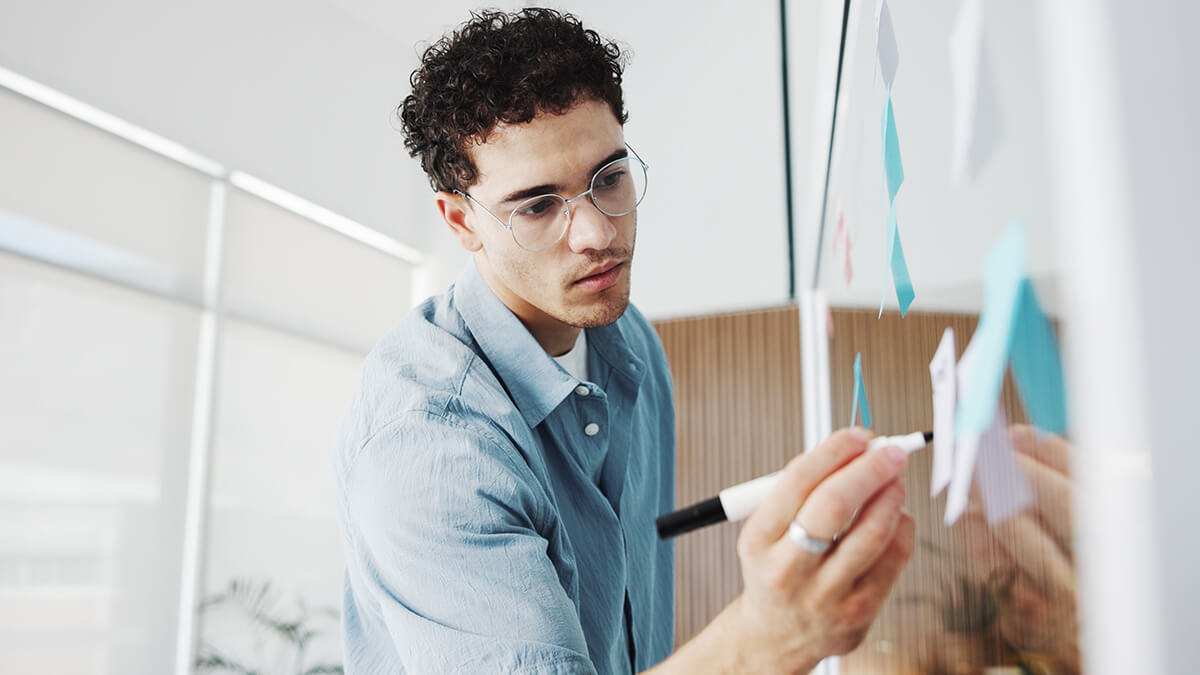 Man writing or planning on glass board in the office.