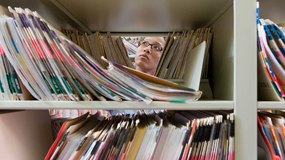 Person searching through shelves of files in an archive.