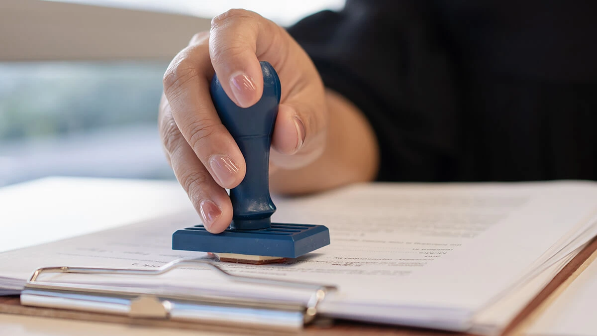 Hand stamping an approval document.
